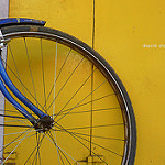 Wheel of a Blue bike on a Yellow wall
